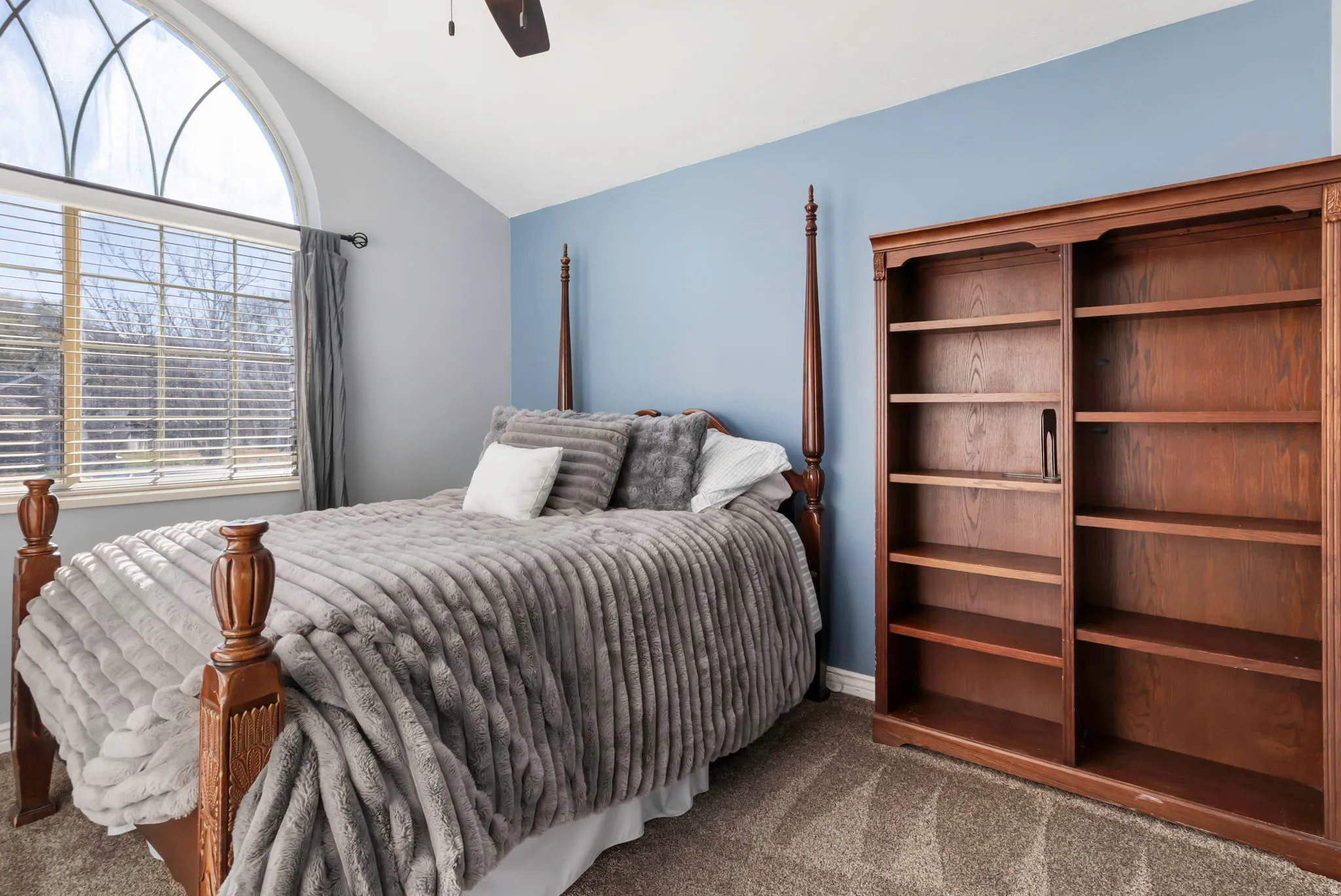 Carpeted bedroom featuring lofted ceiling and a ceiling fan