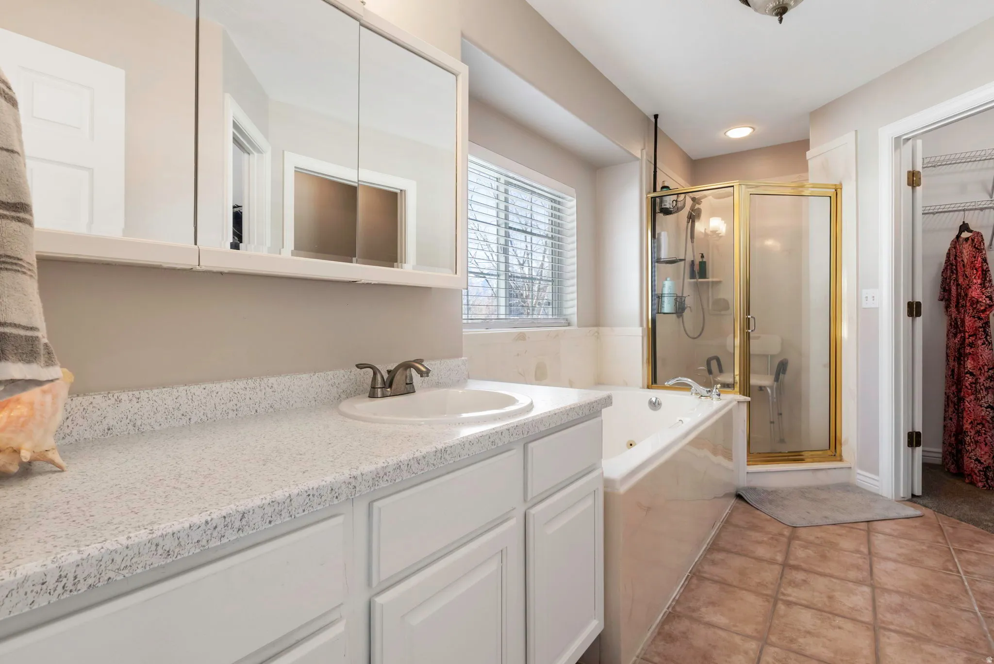 Bathroom featuring a shower stall, a walk in closet, vanity, a garden tub, and light tile patterned flooring