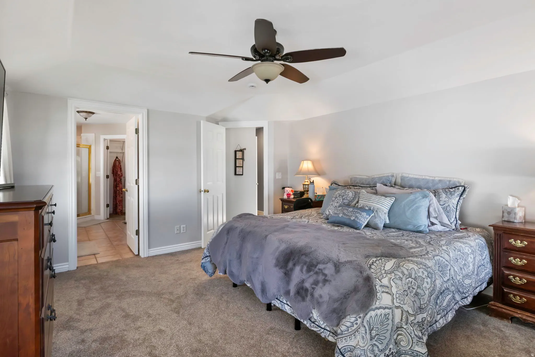 Bedroom with light carpet, a ceiling fan, and ensuite bathroom