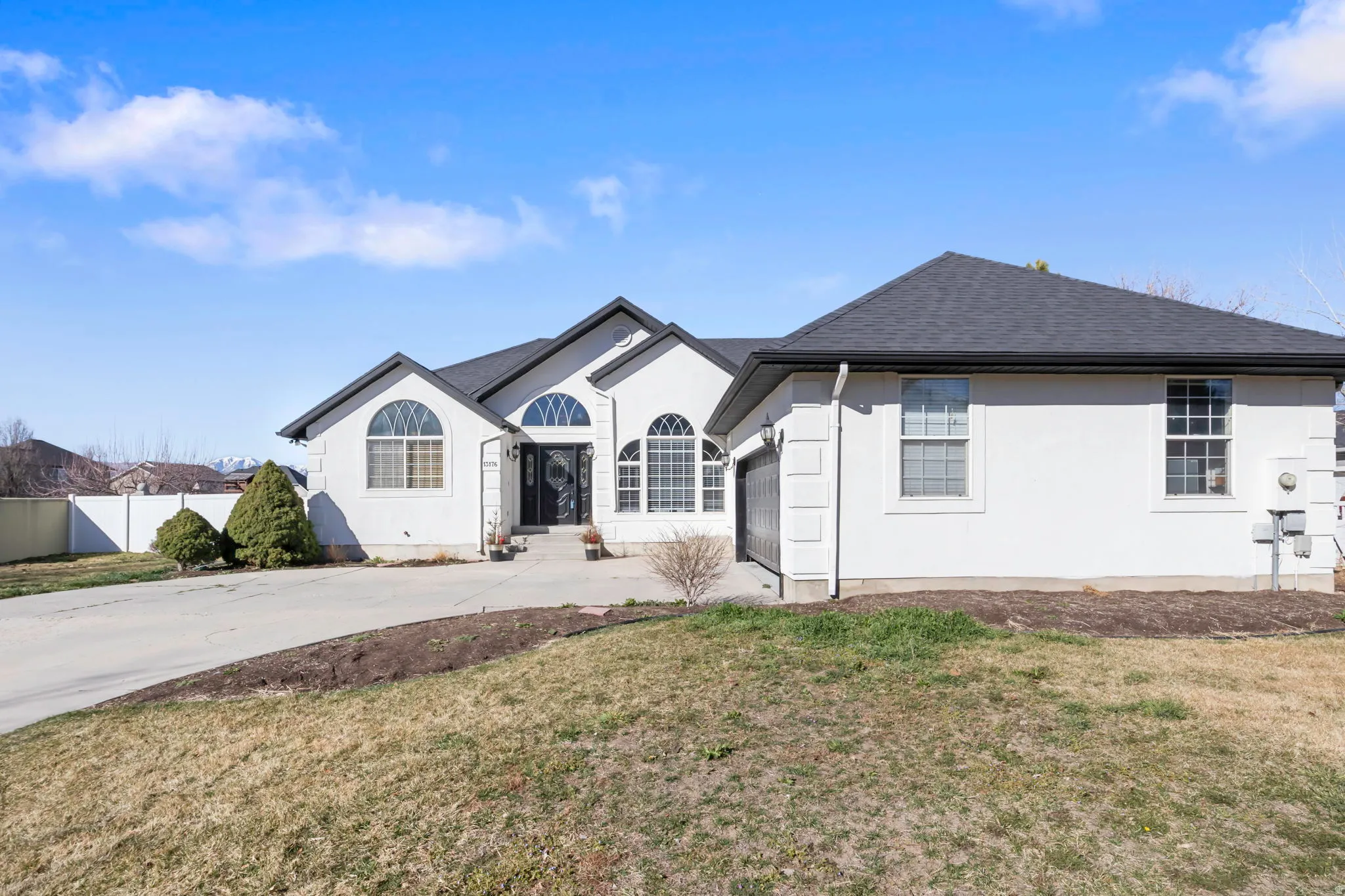 Single story home with concrete driveway, a shingled roof, an attached garage, and stucco siding
