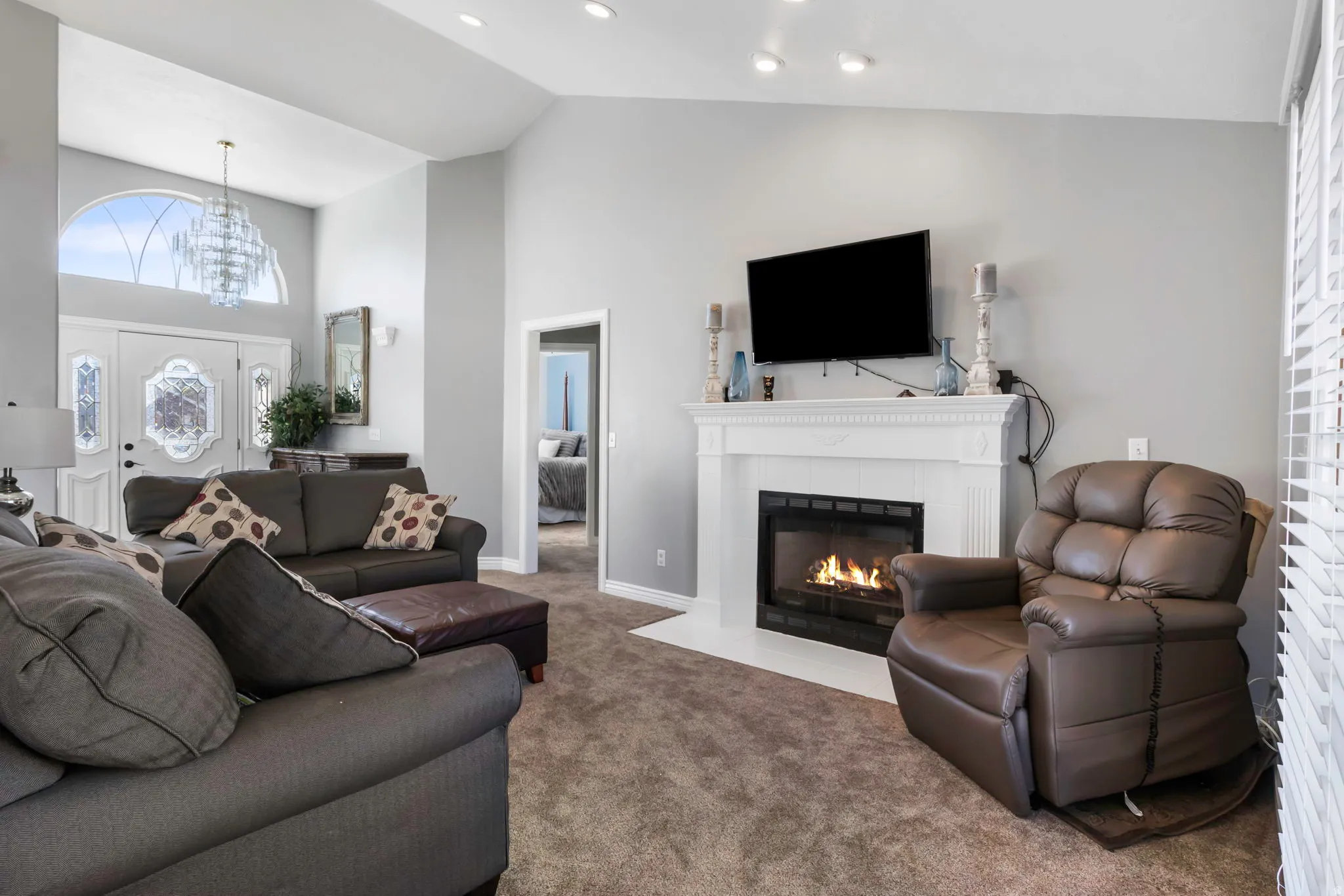 Carpeted living room with a tile fireplace, vaulted ceiling, and hanging lights