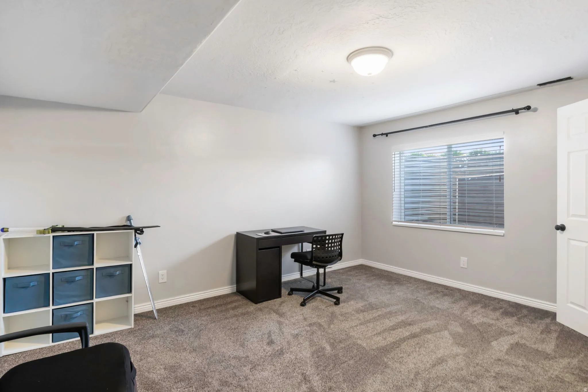 Carpeted office space featuring baseboards and a textured ceiling