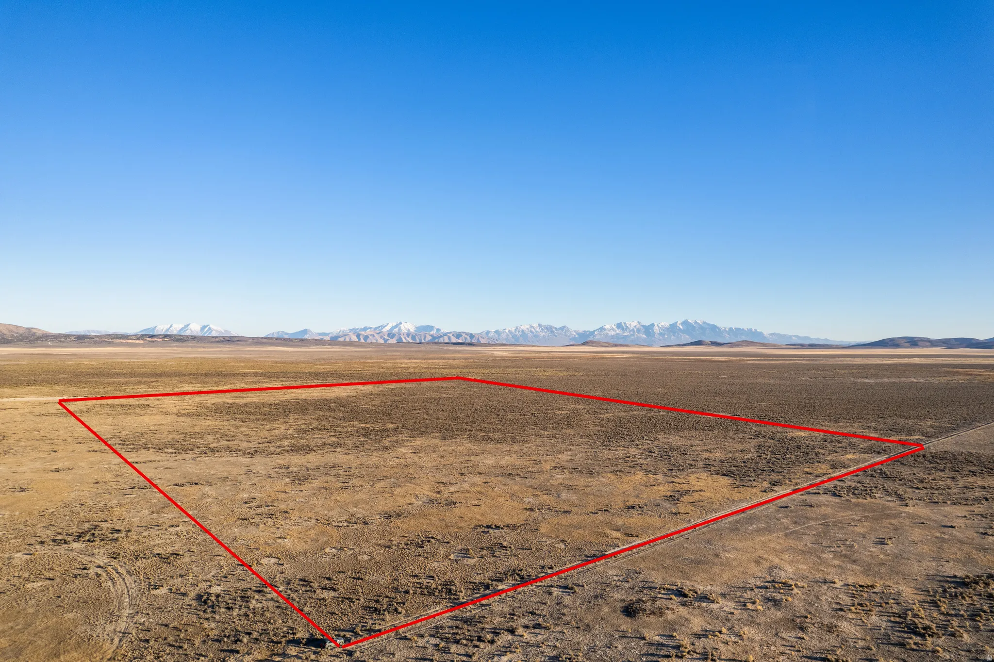 Aerial view of sparsely populated area featuring property parcel outlined and a mountainous background