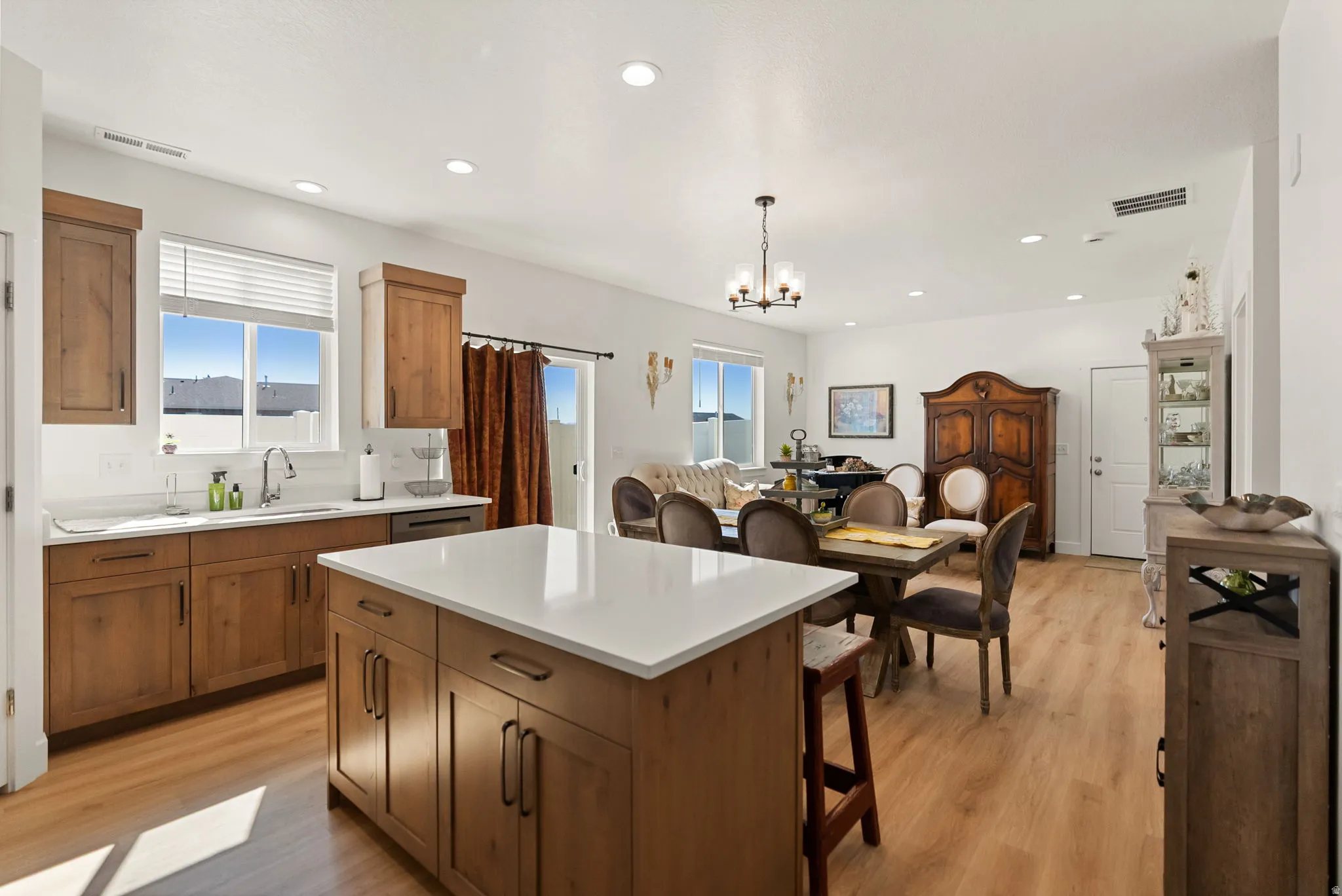 Kitchen featuring wood finish cabinets, suspended lighting, a center island, and light wood-style flooring