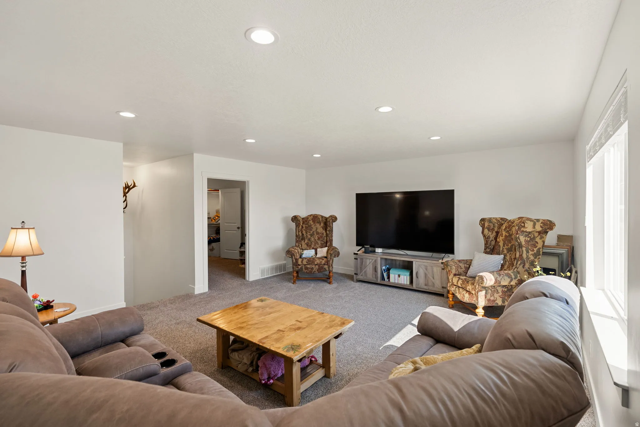 Carpeted living area featuring recessed lighting and baseboards