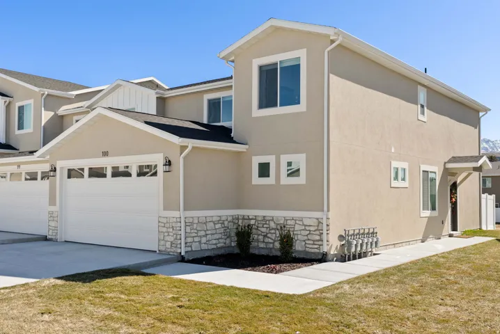 View of home's exterior featuring stone siding, a lawn, stucco siding, and concrete driveway