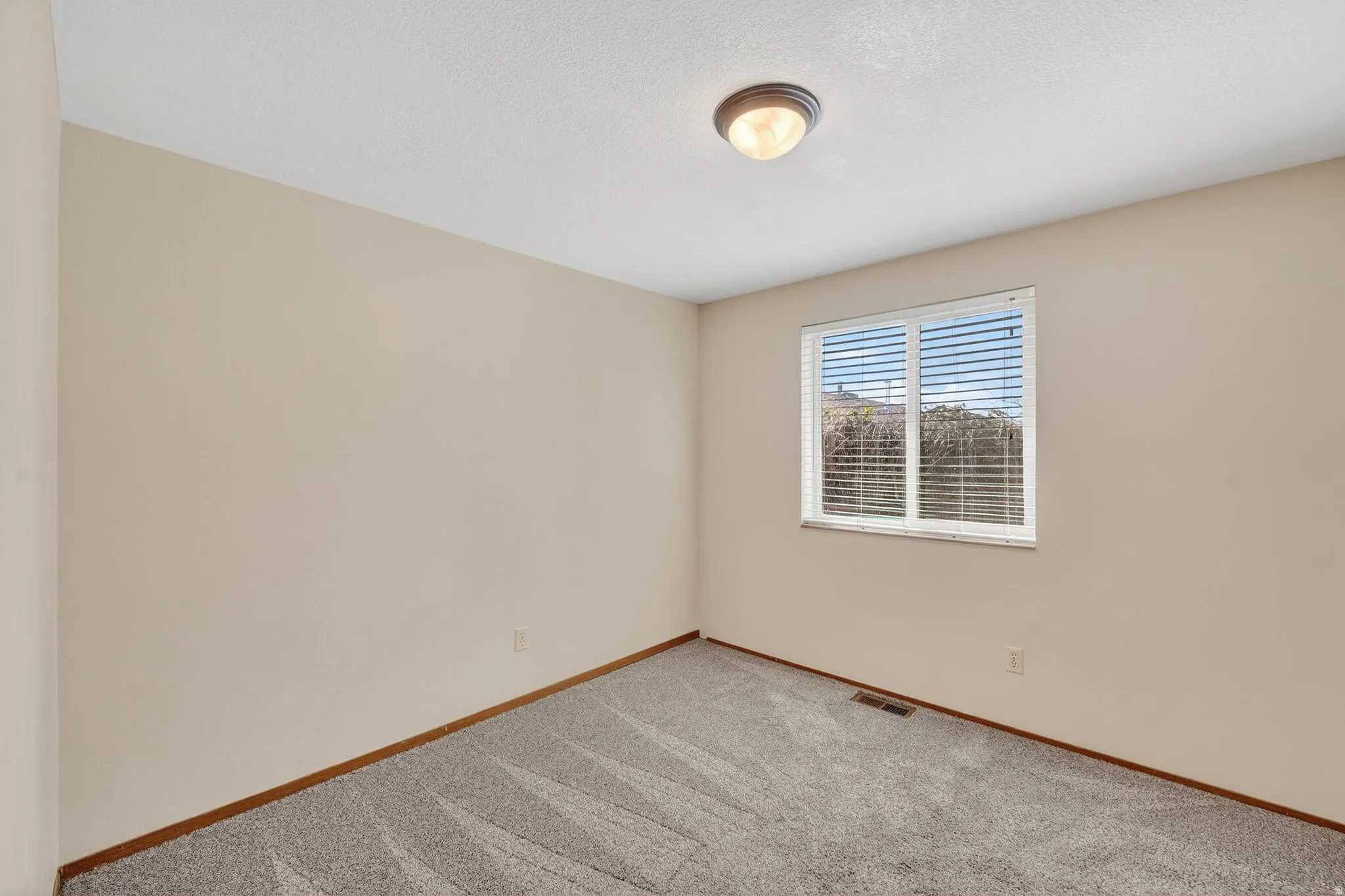 Empty room featuring light colored carpet and baseboards