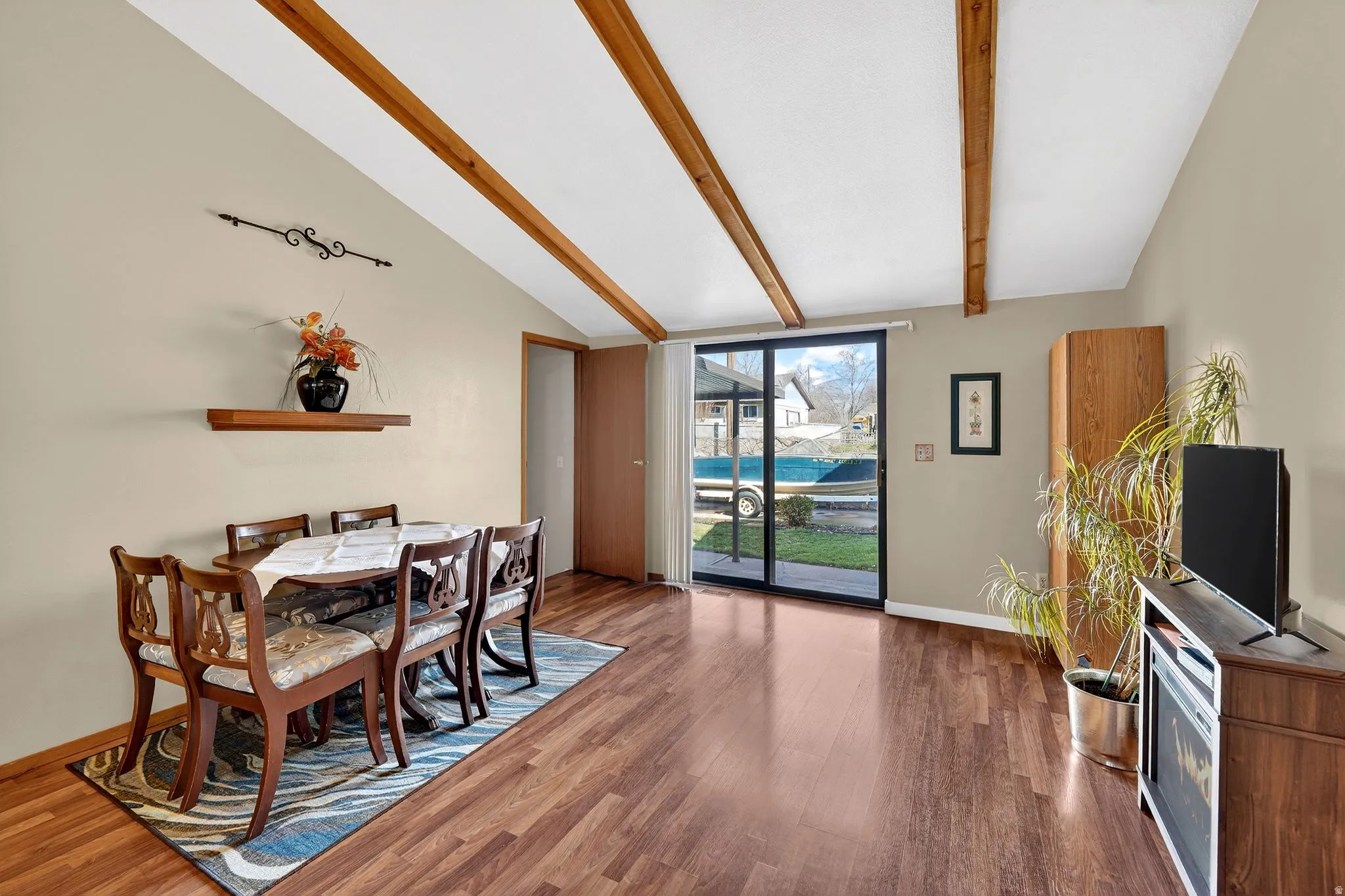Dining space with lofted ceiling with beams and wood finished floors