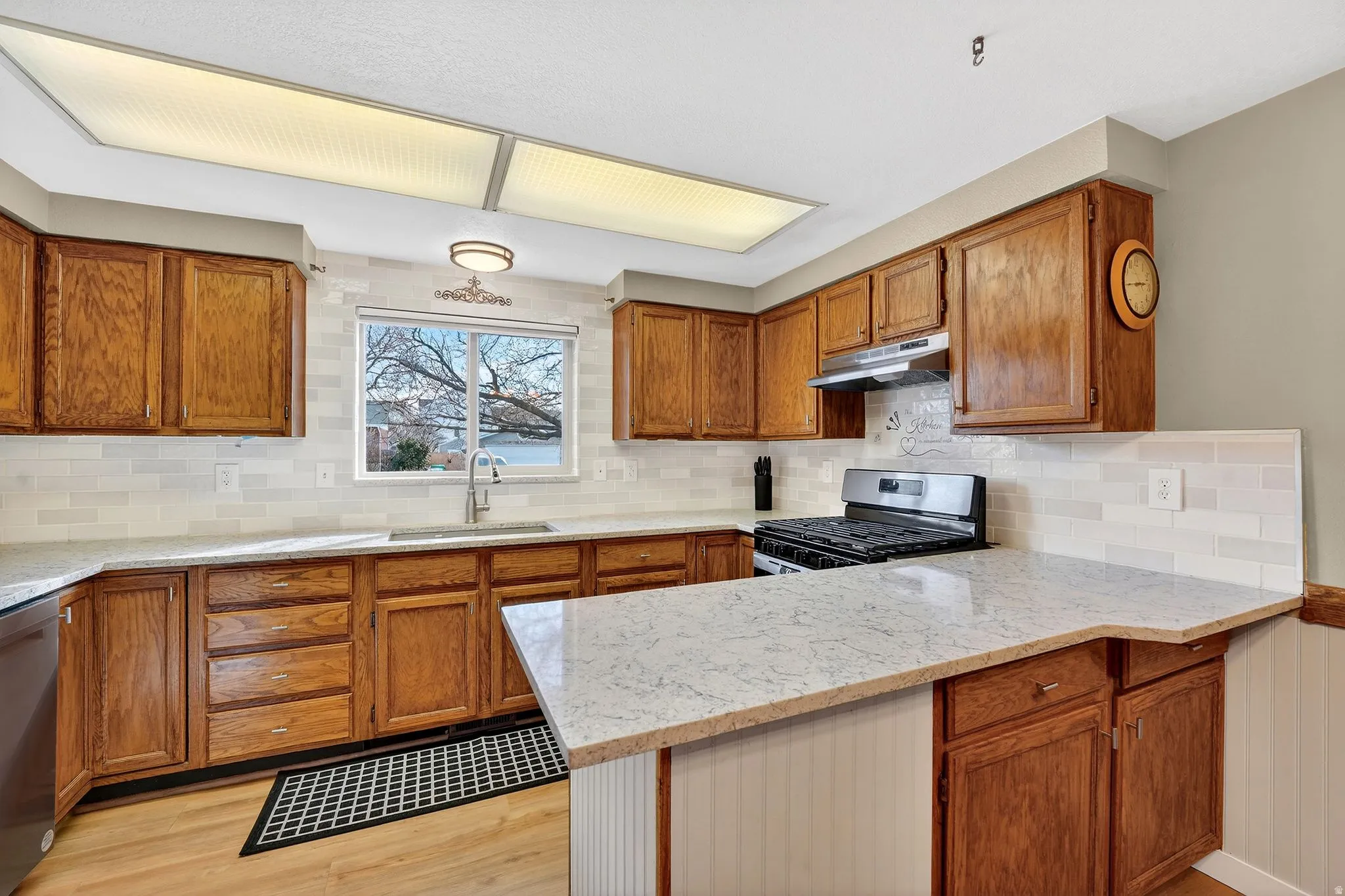Kitchen with wood finish cabinets, a peninsula, and light stone countertops