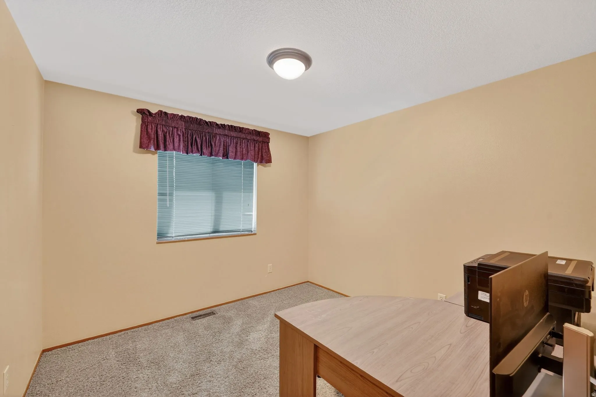 Home office with light colored carpet and baseboards