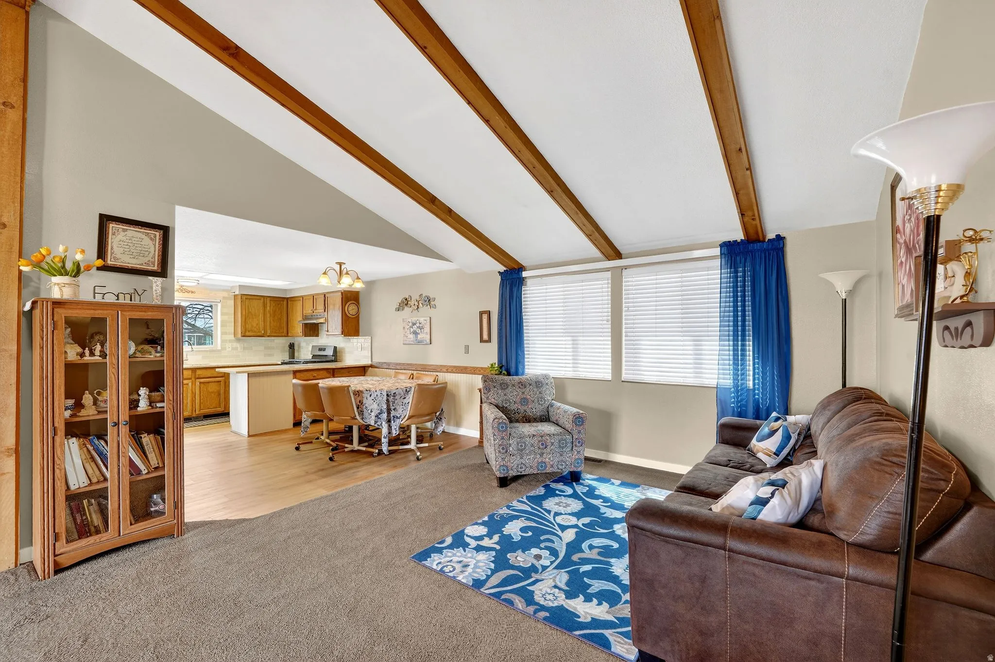 Living room featuring lofted ceiling with beams and light colored carpet