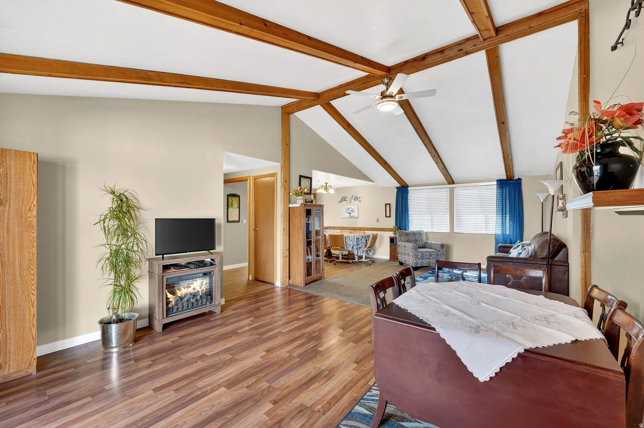 Dining space featuring wood finished floors, lofted ceiling with beams, ceiling fan, and a chandelier