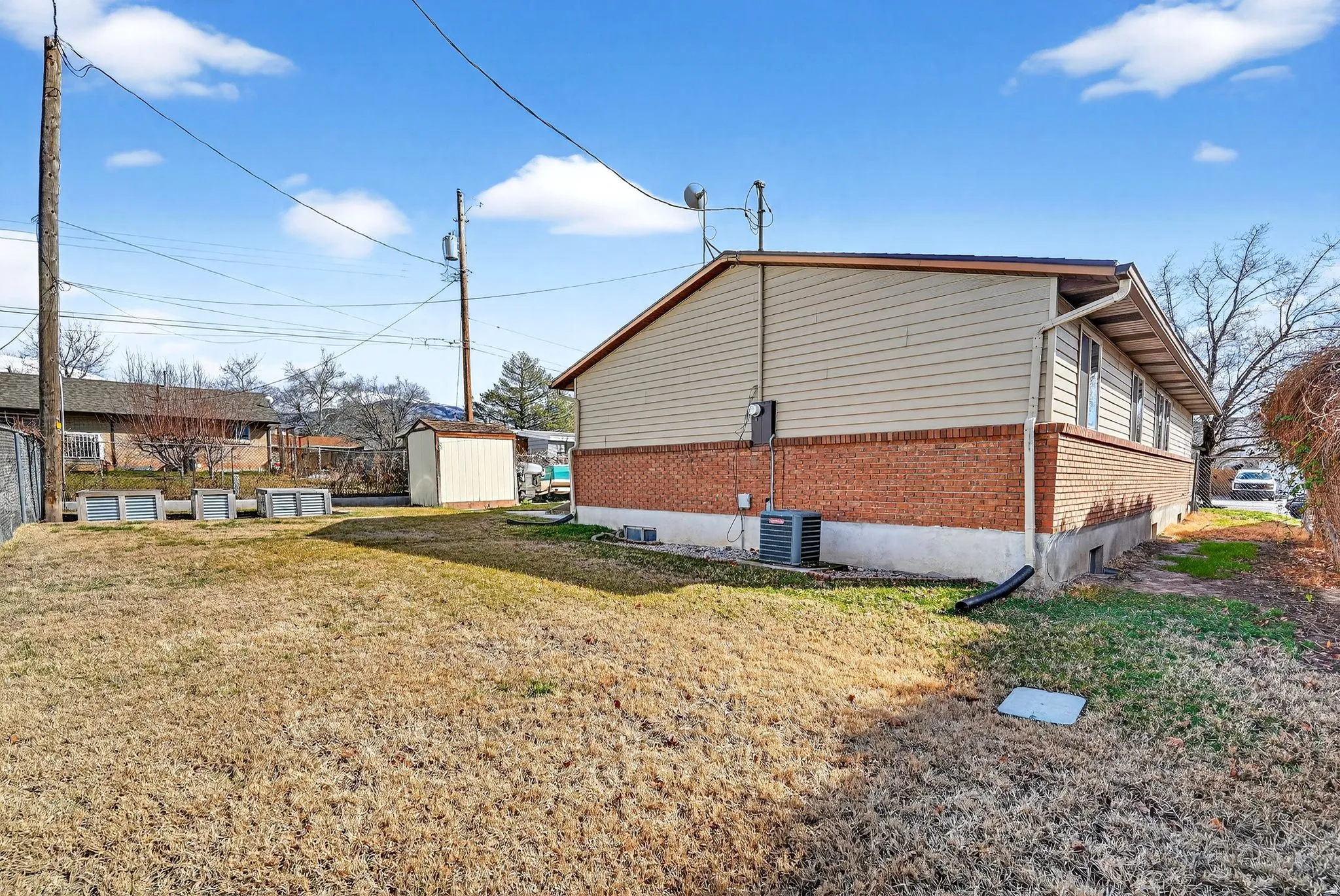 View of side of property with a storage shed, brick siding, and a lawn