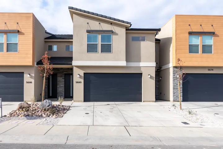View of front of house featuring stone siding, stucco siding, and a garage