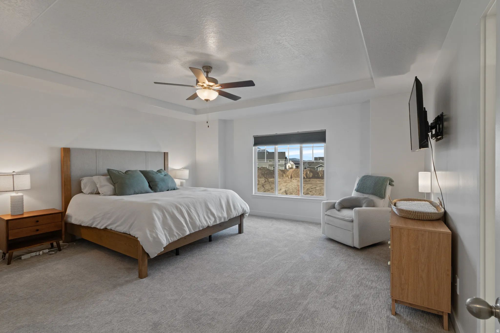 Carpeted bedroom featuring a tray ceiling, a textured ceiling, and a ceiling fan