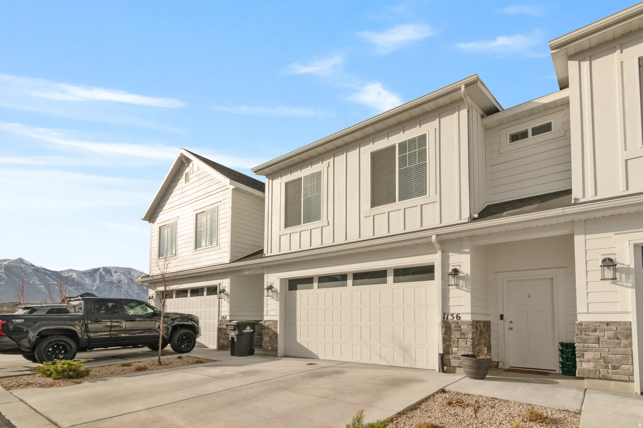 View of front of home featuring stone siding, an attached garage, concrete driveway, board and batten siding, and a mountain view