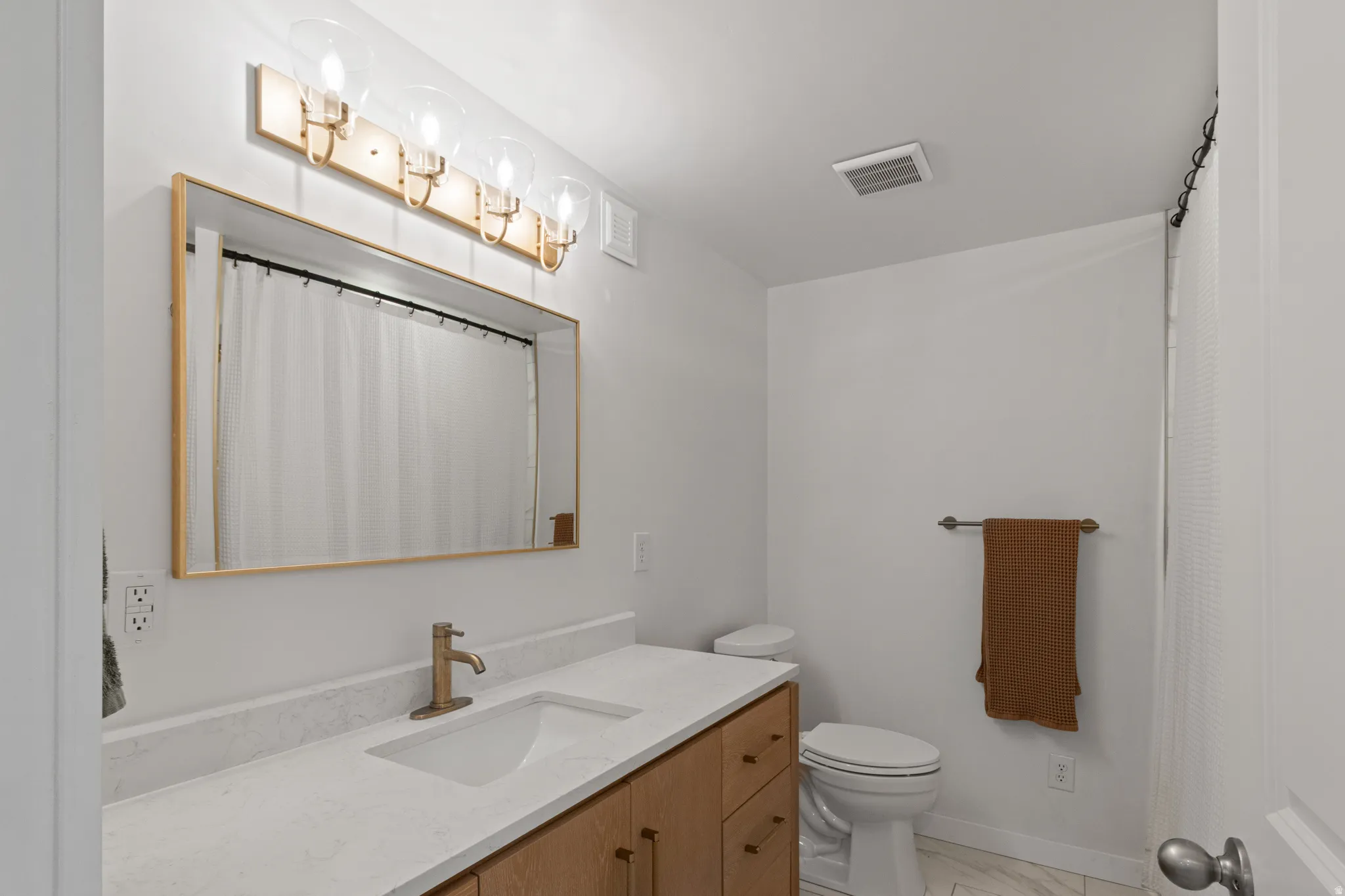 Bathroom with vanity, curtained shower, and light marble finish flooring