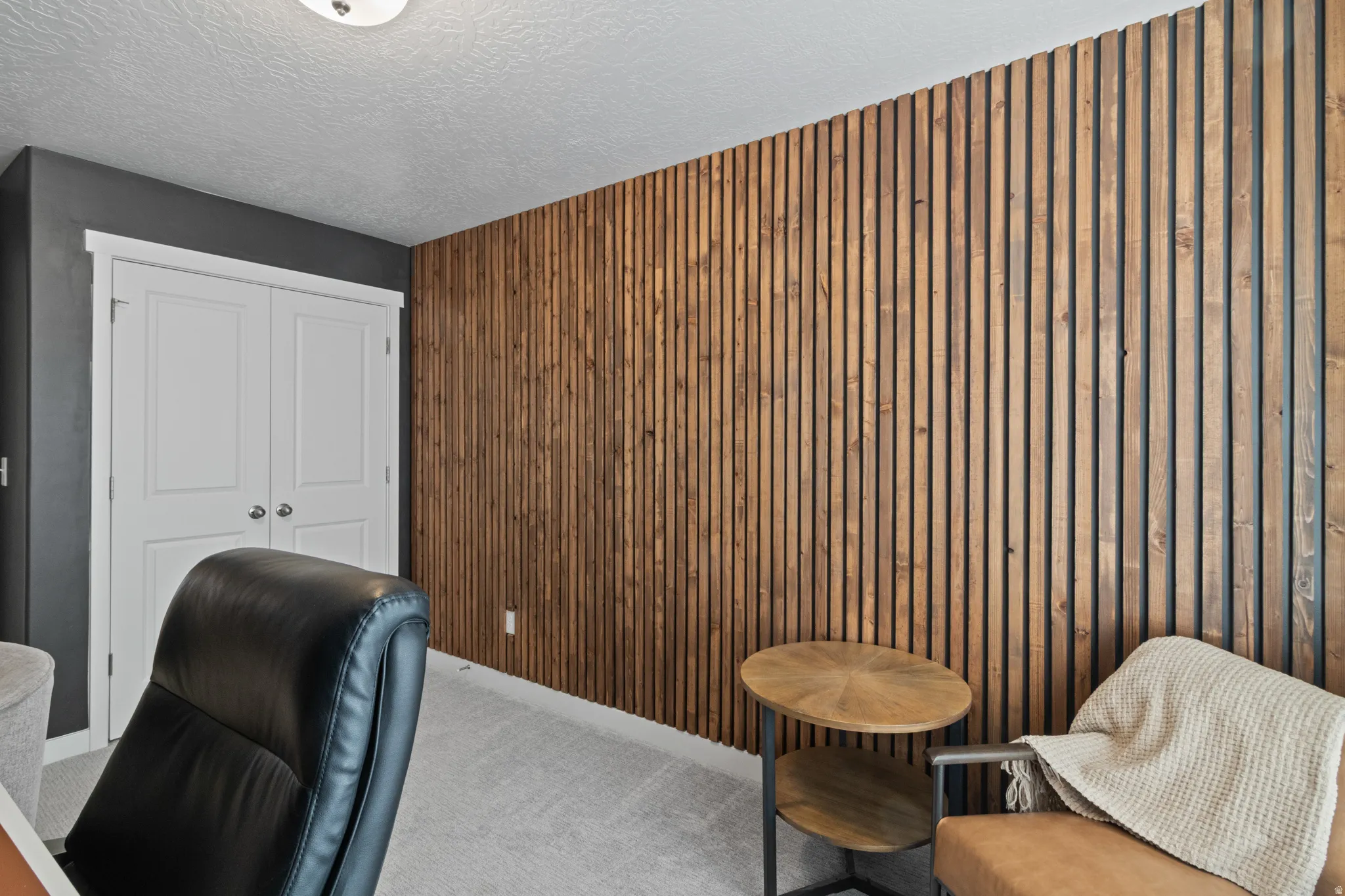Carpeted home office with a textured ceiling and wooden walls