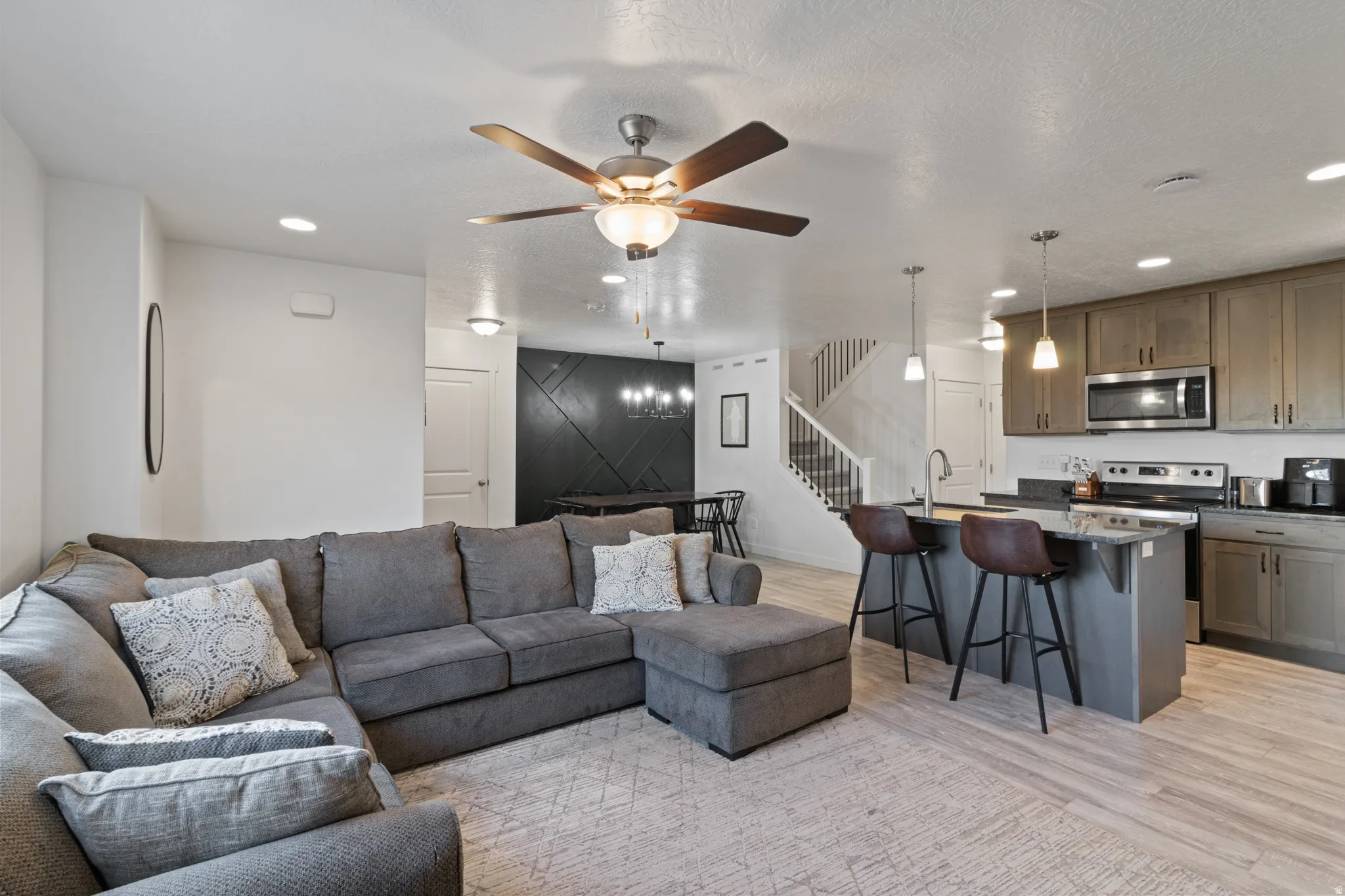Living room featuring recessed lighting, light wood-type flooring, ceiling fan, and a textured ceiling
