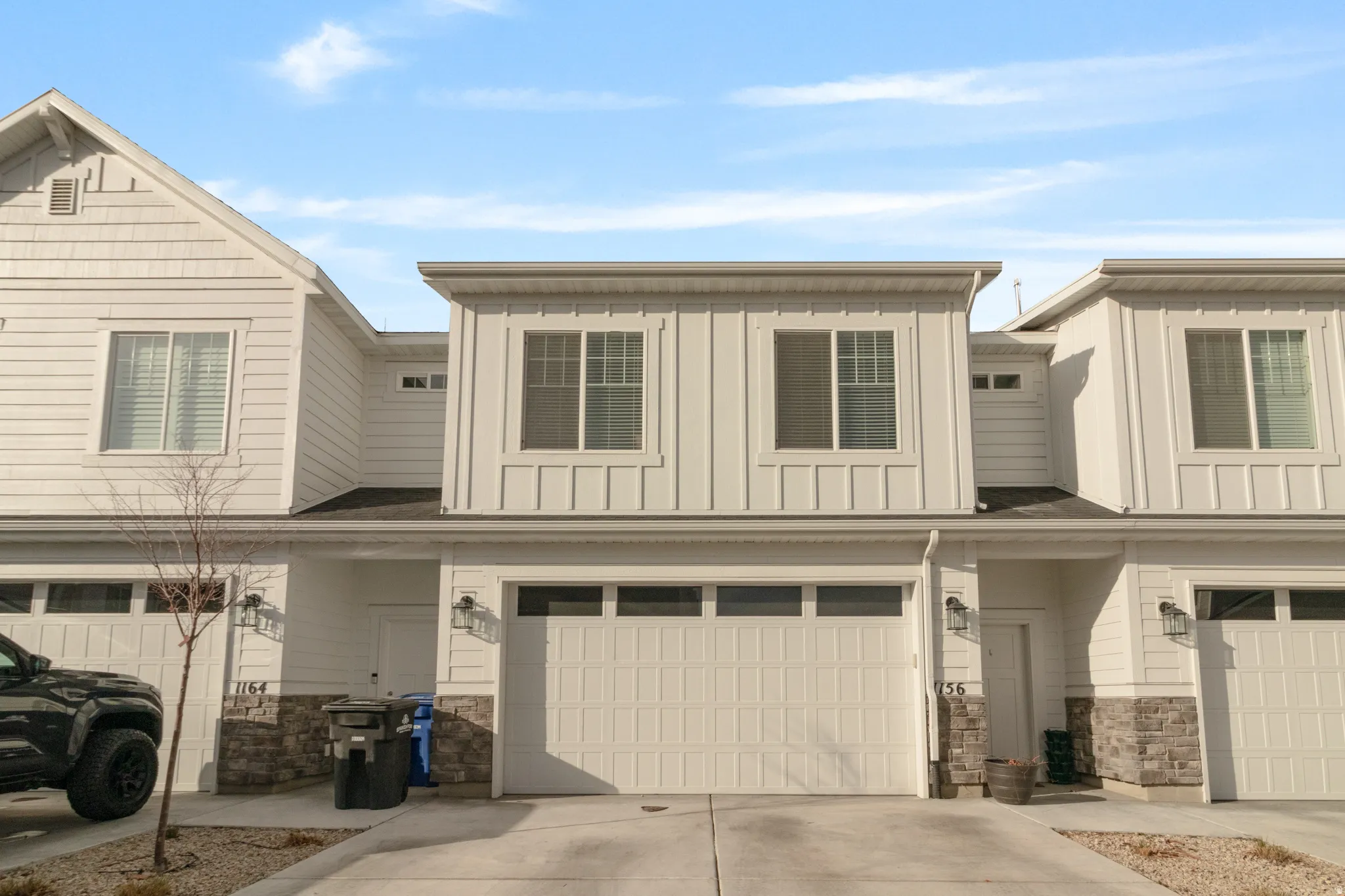 Craftsman house with stone siding, an attached garage, board and batten siding, and driveway