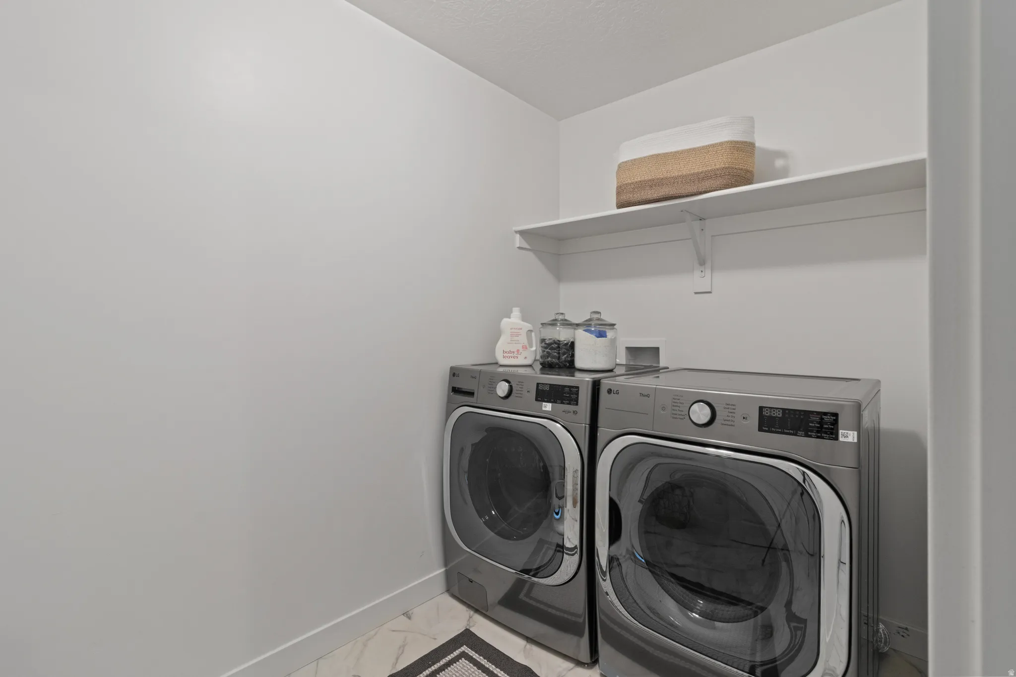 Laundry room with light marble finish flooring and washer and dryer