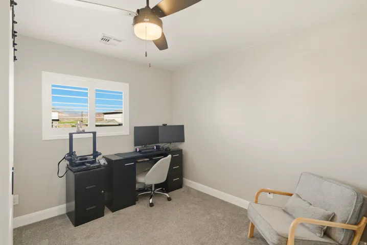 Office with light colored carpet and a ceiling fan