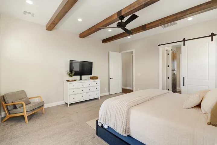 Bedroom with a barn door, recessed lighting, light colored carpet, ceiling fan, and beam ceiling