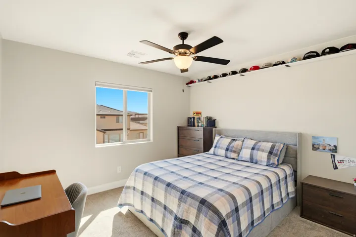 Bedroom with light colored carpet and a ceiling fan