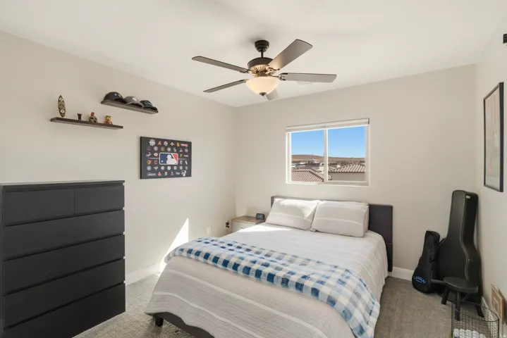 Carpeted bedroom featuring a ceiling fan and baseboards