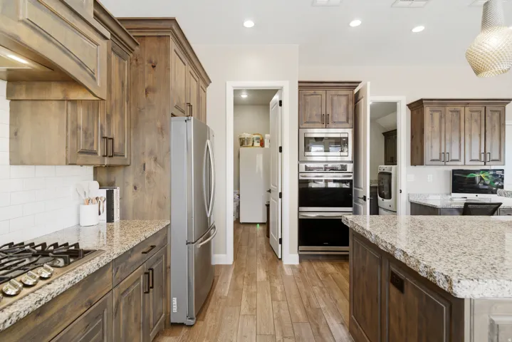 Kitchen featuring light stone countertops, stainless steel appliances, tasteful backsplash, light wood-style flooring, and recessed lighting