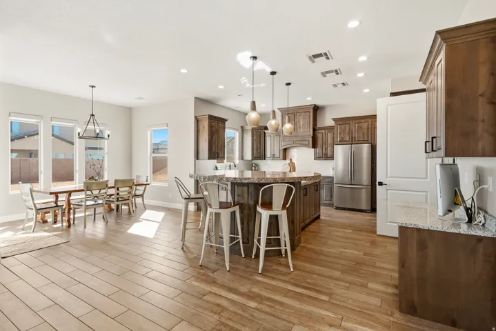 Kitchen featuring a center island, dark stone countertops, freestanding refrigerator, a kitchen bar, and suspended lighting