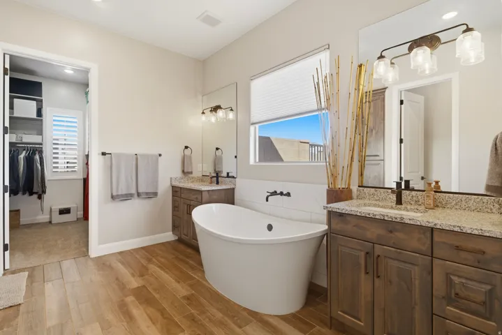 Bathroom featuring two vanities, light wood-style floors, a freestanding bath, recessed lighting, and a spacious closet