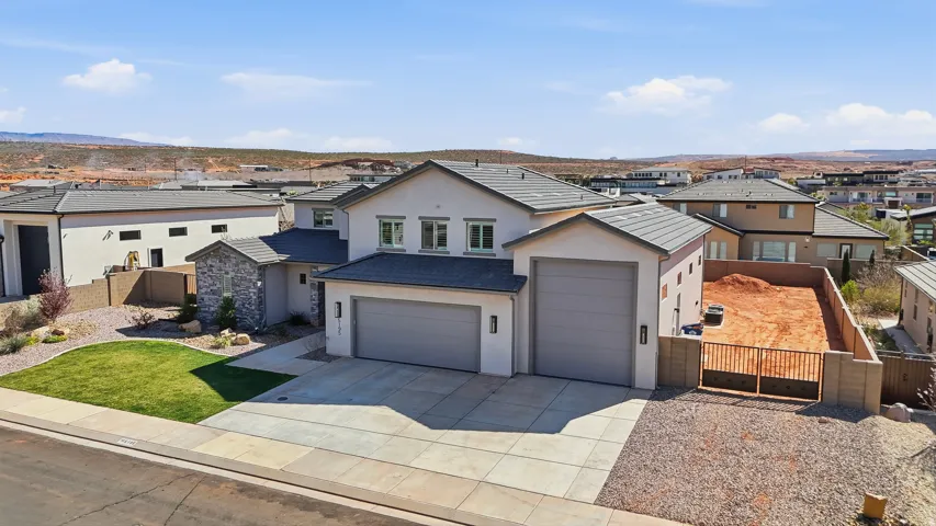 View of front of home with stucco siding, a gate, driveway, a residential view, and an attached garage