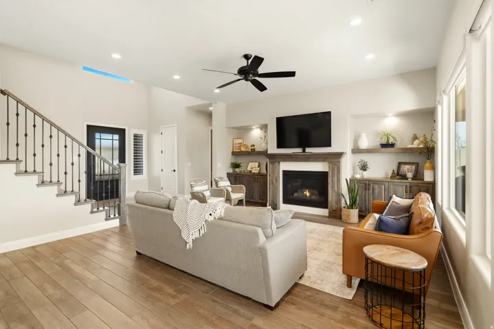 Living area with a ceiling fan, light wood-style flooring, a glass covered fireplace, and recessed lighting