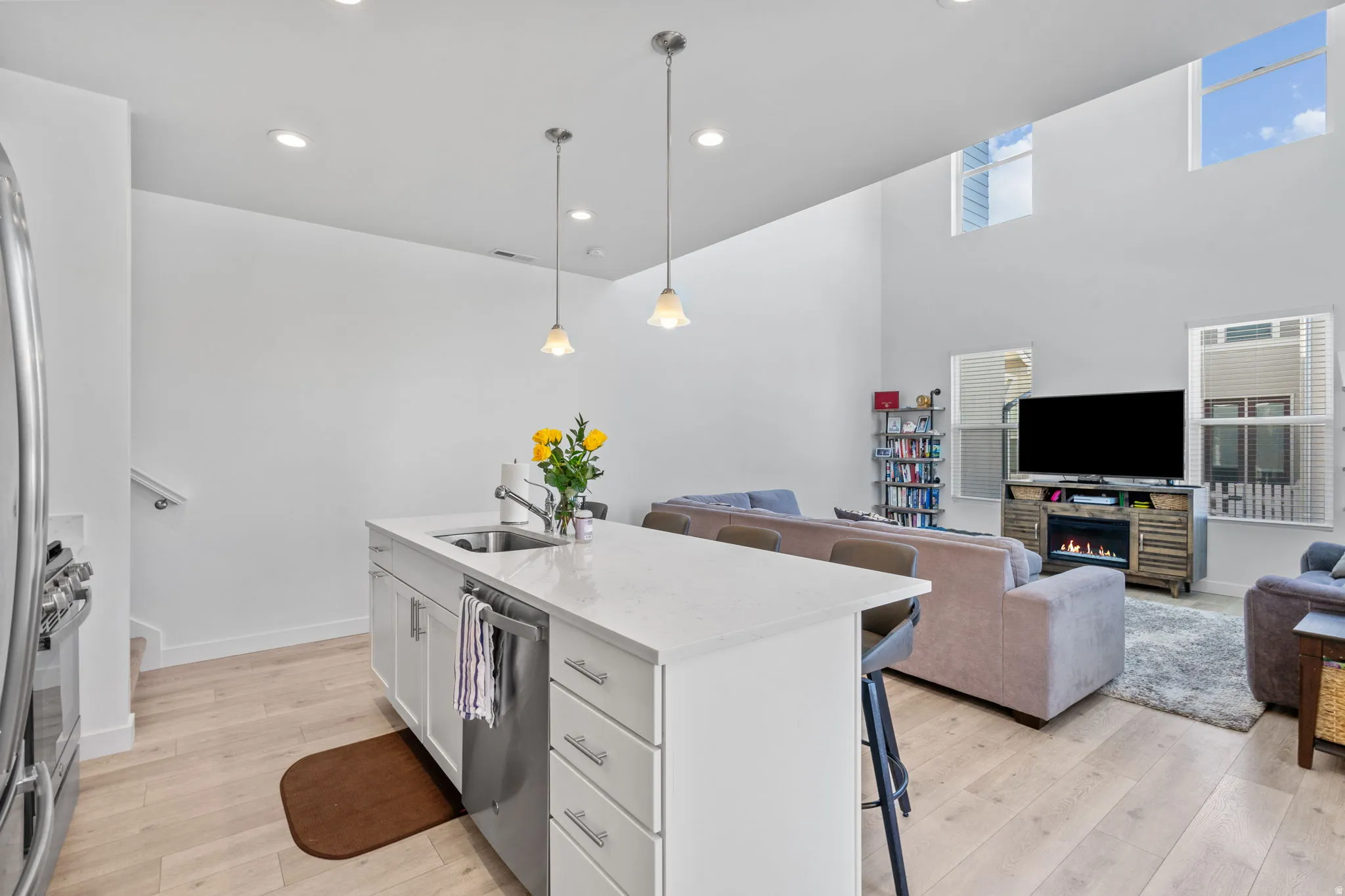 Kitchen featuring open floor plan, a breakfast bar area, light wood-style flooring, a center island with sink, and light stone counters