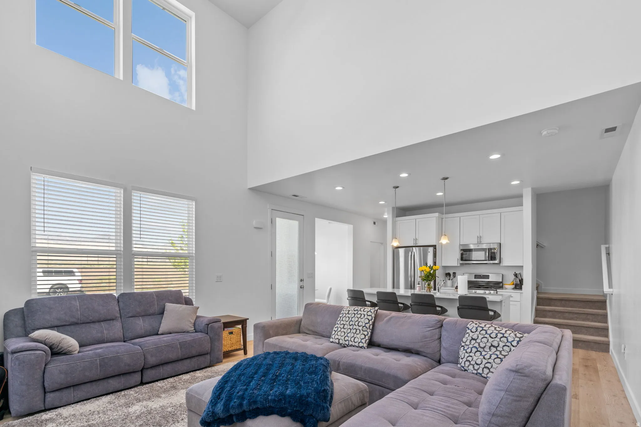 Living room featuring healthy amount of natural light, light wood finished floors, a high ceiling, and french doors