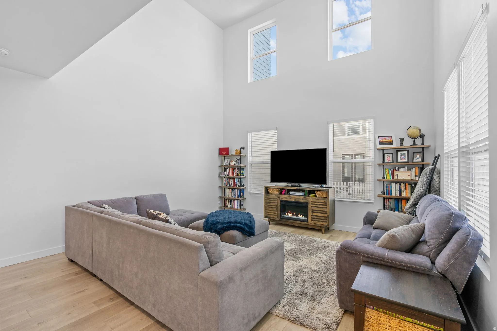 Living room featuring light wood-style flooring and a high ceiling