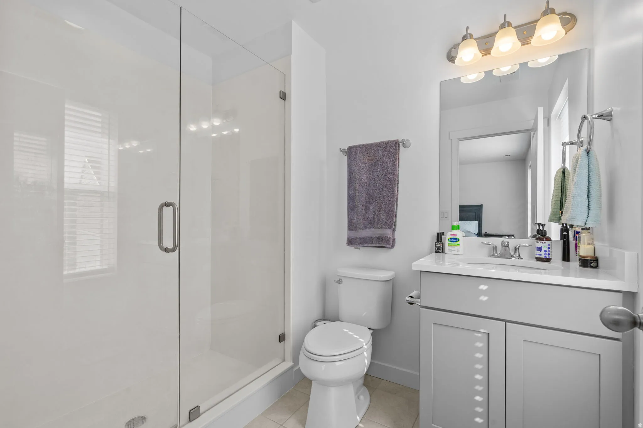 Full bathroom with vanity, a shower stall, and light tile patterned floors