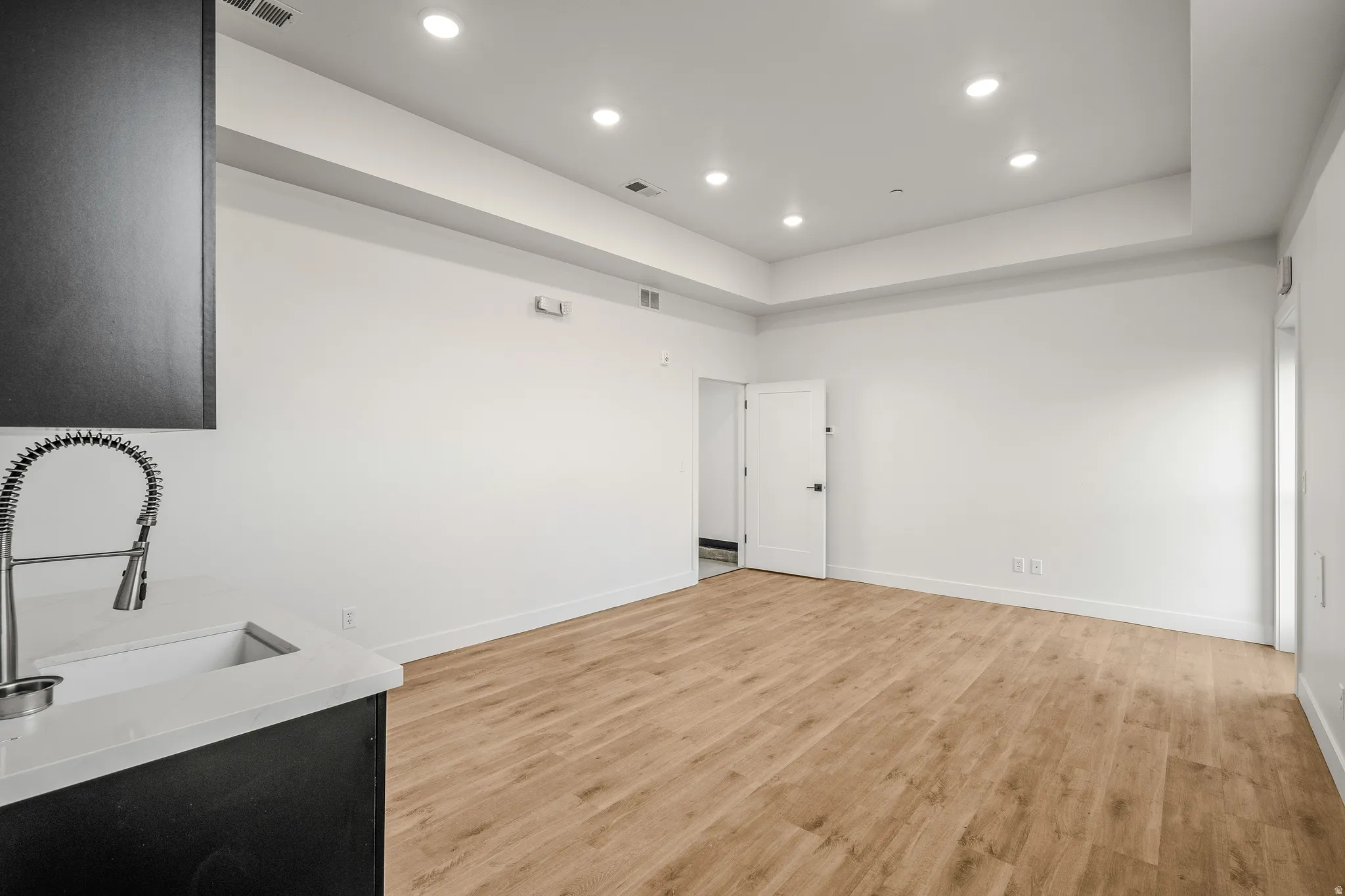 Unfurnished living room with recessed lighting, light wood finished floors, and a raised ceiling