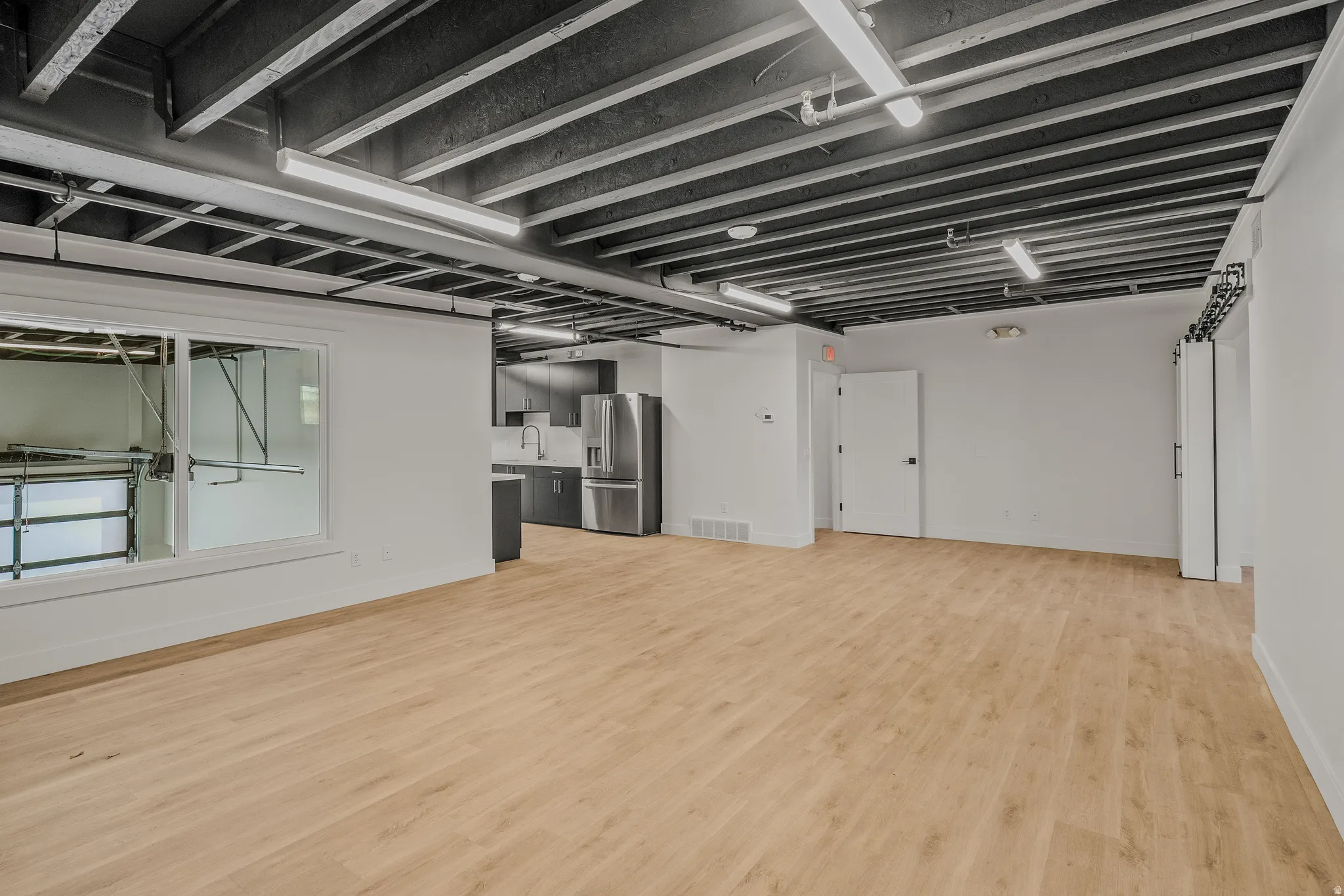 Below grade area featuring stainless steel fridge and light wood-type flooring