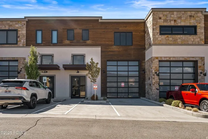 Contemporary house with stone siding, stucco siding, and uncovered parking