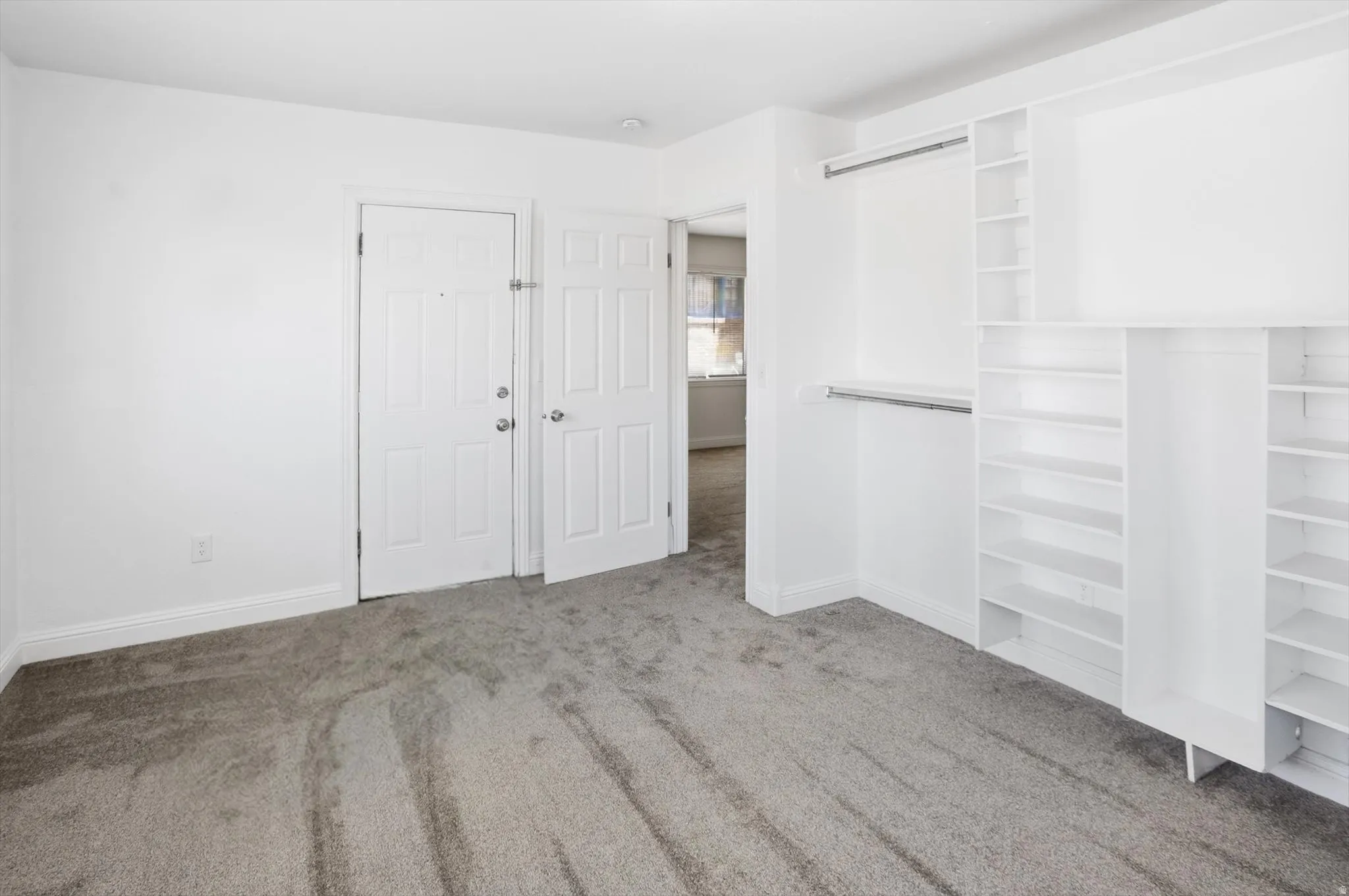 Unfurnished bedroom featuring light carpet and baseboards