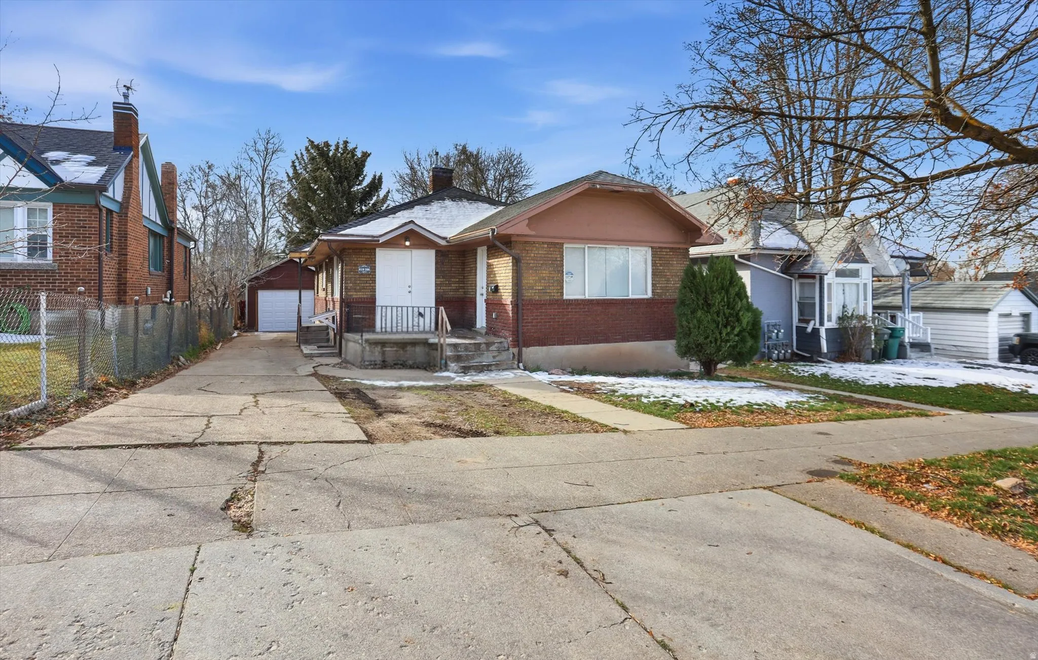 View of front facade with brick siding, an outbuilding, a detached garage, and a chimney