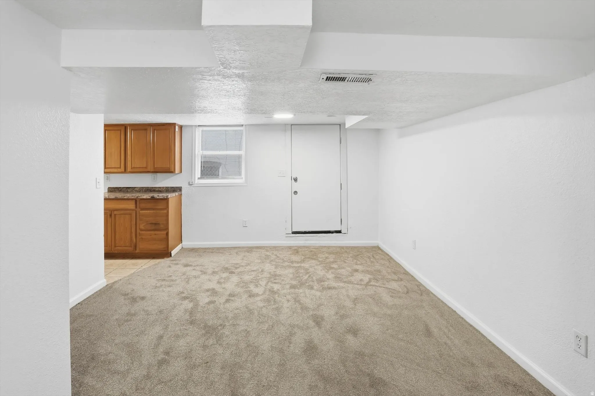 Finished below grade area with light carpet and a textured ceiling