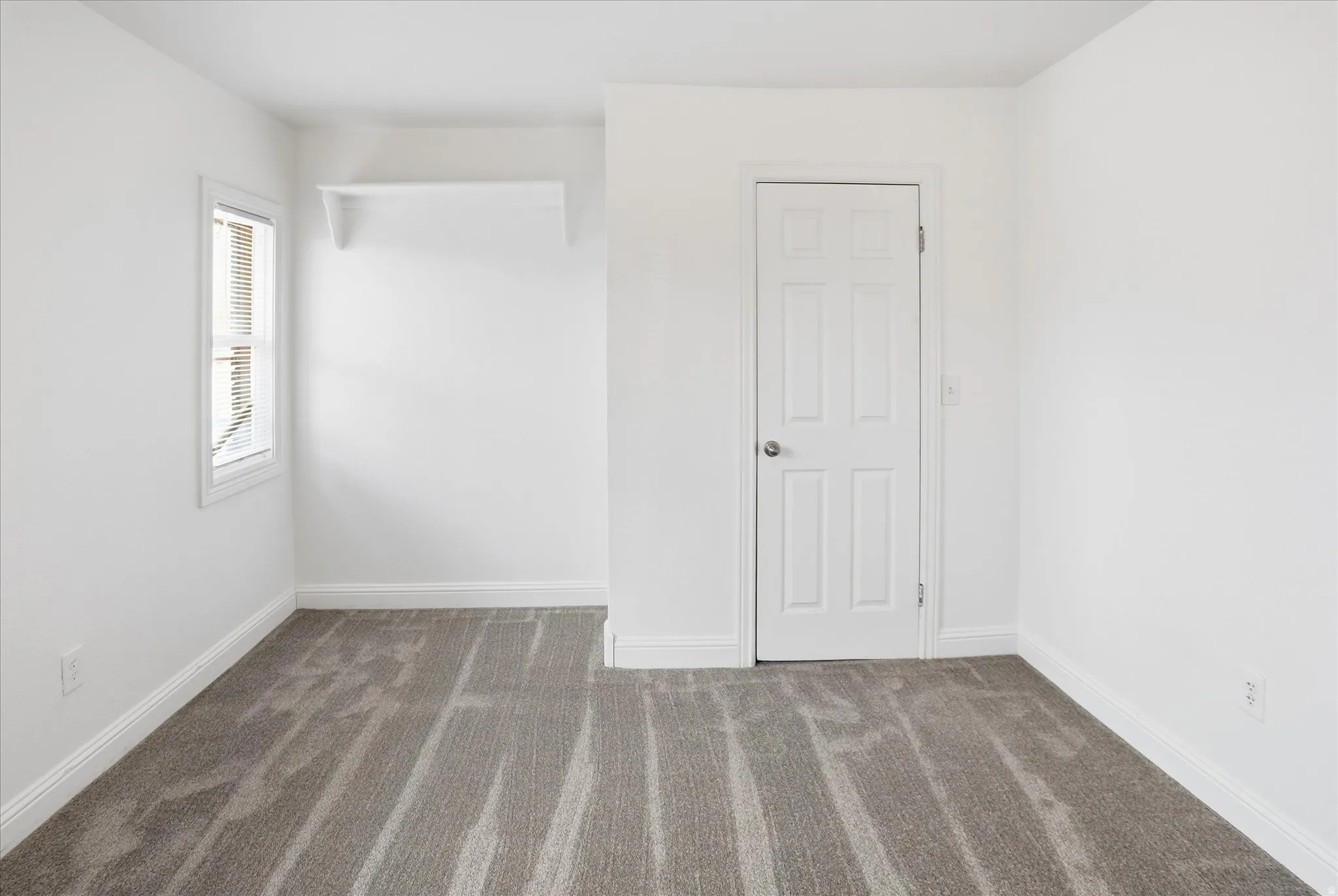 Empty room with dark carpet and baseboards