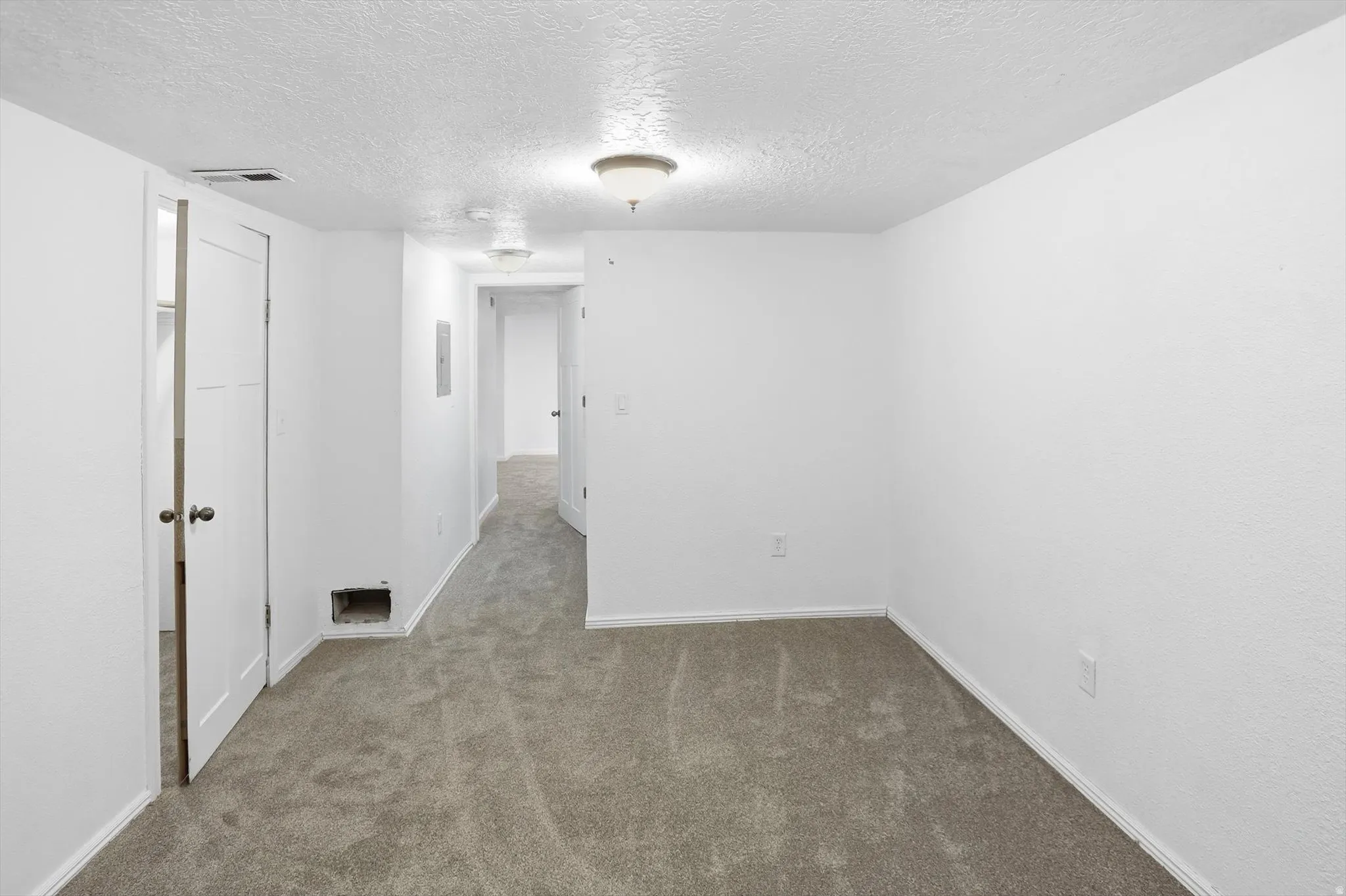 Unfurnished room featuring a textured ceiling and carpet