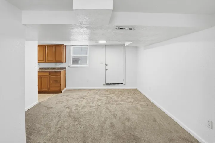 Finished below grade area with light carpet and a textured ceiling