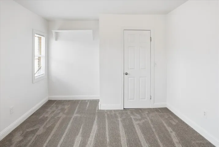 Empty room with dark carpet and baseboards
