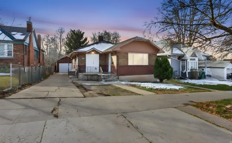 View of front facade with an outdoor structure, brick siding, a detached garage, and a chimney