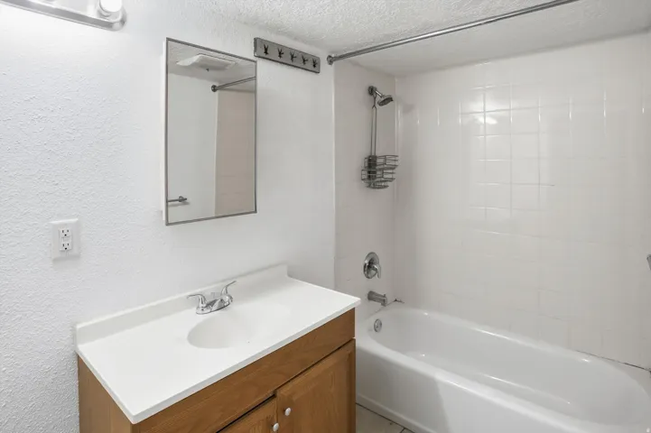 Bathroom with vanity, a textured ceiling, shower / bath combination, and a textured wall